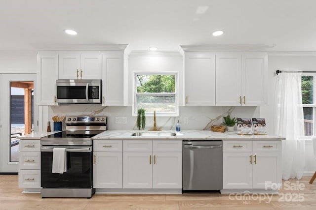 5910 Grosner Pl, Charlotte, NC 28211 - kitchen featuring stainless steel appliances, a sink, white cabinets, healthy amount of natural light, and ornamental molding