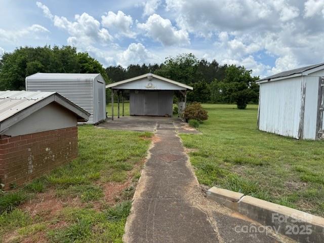 2165 Mccraw Rd, Mooresboro, NC 28114 - view of green lawn featuring an outbuilding, a carport, driveway, and a storage shed
