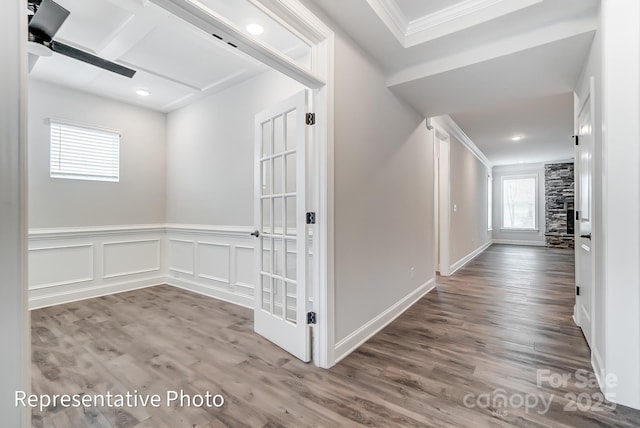 hallway with crown molding, wood finished floors, and a wainscoted wall