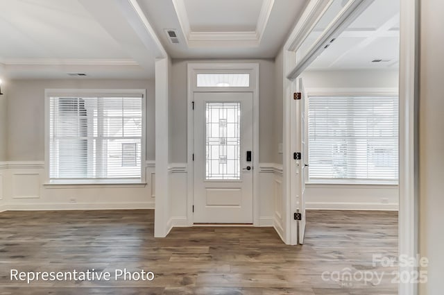 foyer entrance featuring ornamental molding, wood finished floors, a wainscoted wall, plenty of natural light, and a decorative wall