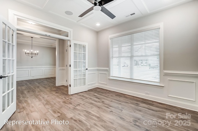 spare room with french doors, a decorative wall, ceiling fan, a chandelier, and wood finished floors