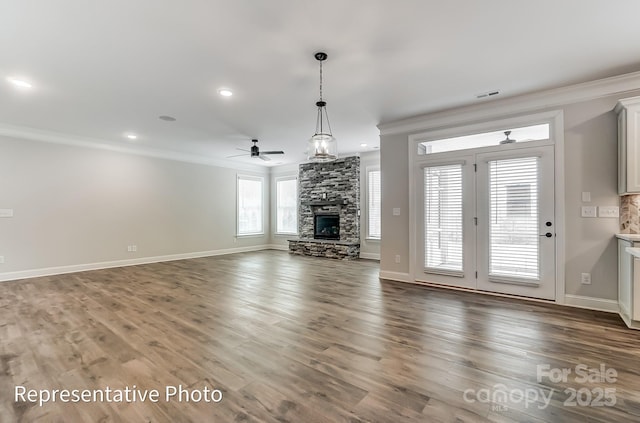 unfurnished living room featuring crown molding, a stone fireplace, a ceiling fan, baseboards, and wood finished floors