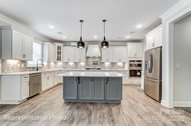 kitchen featuring stainless steel appliances, custom range hood, light countertops, white cabinets, and recessed lighting