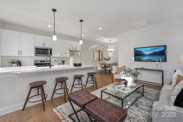 living room with light wood finished floors, a chandelier, recessed lighting, and baseboards