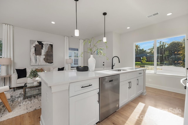 kitchen with stainless steel dishwasher, light wood finished floors, a kitchen island with sink, decorative light fixtures, and recessed lighting
