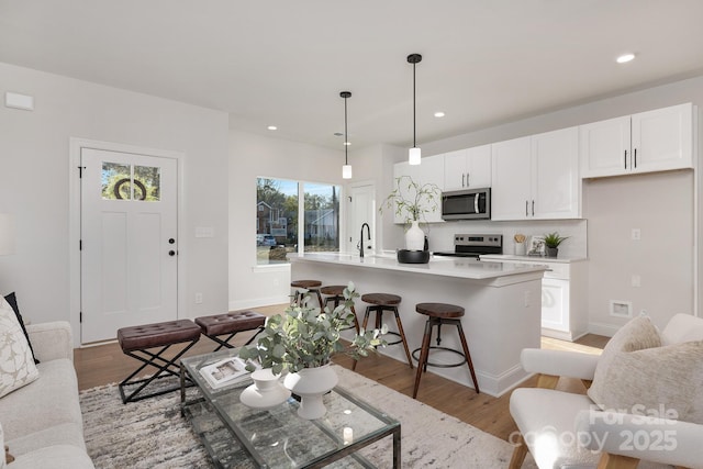 living room featuring light wood-type flooring, recessed lighting, and baseboards