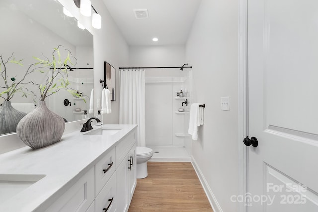 full bath with wood finished floors, curtained shower, double vanity, toilet, and recessed lighting