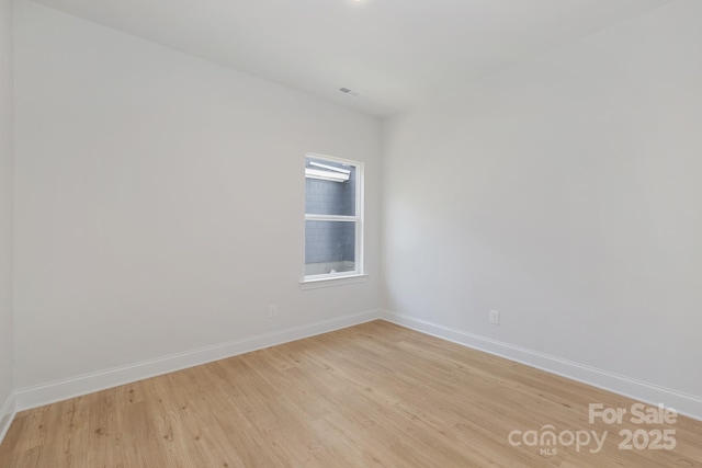 empty room with baseboards and light wood-type flooring