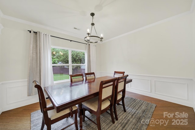 2117 Seabrook Ln, Fort Mill, SC 29715 - dining area featuring a chandelier, dark wood finished floors, crown molding, wainscoting, and a decorative wall