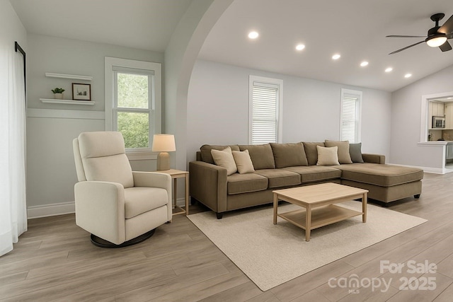 living area with a ceiling fan, arched walkways, light wood-style flooring, recessed lighting, and lofted ceiling