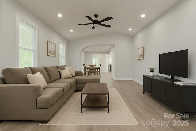 living area with light wood-type flooring, plenty of natural light, lofted ceiling, recessed lighting, and arched walkways