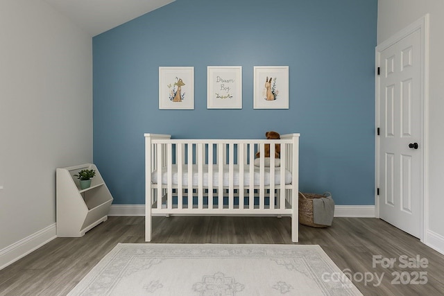 bedroom with wood finished floors, lofted ceiling, and baseboards