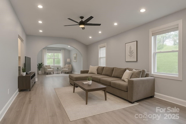 living area featuring arched walkways, light wood-style flooring, ceiling fan, recessed lighting, and baseboards