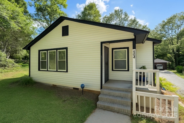 view of front facade featuring crawl space, an outbuilding, and a front yard