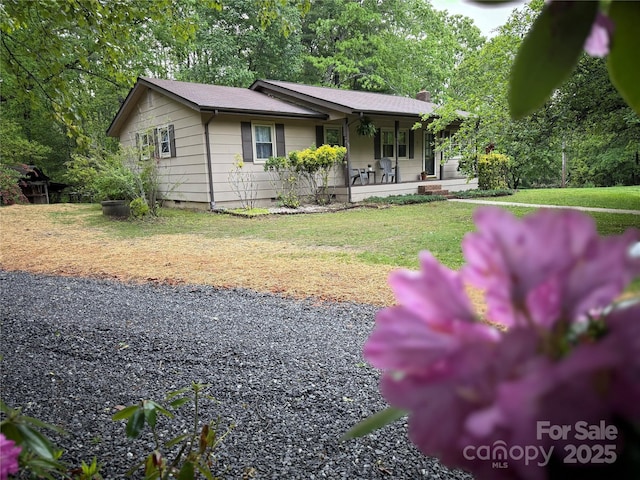 ranch-style home featuring covered porch, crawl space, a chimney, and a front yard
