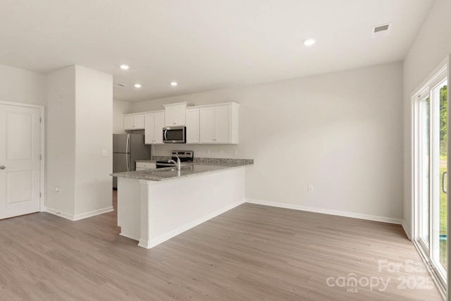 3342 Strong Box Ln, Gastonia, NC 28052 - kitchen with appliances with stainless steel finishes, light wood-type flooring, baseboards, white cabinetry, and a peninsula