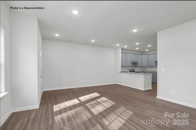 unfurnished living room featuring dark wood-type flooring, recessed lighting, and baseboards