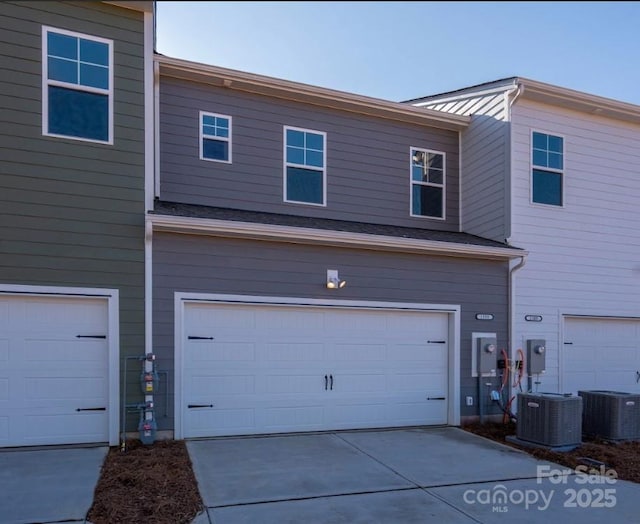 view of side of property with an attached garage, central air condition unit, and driveway