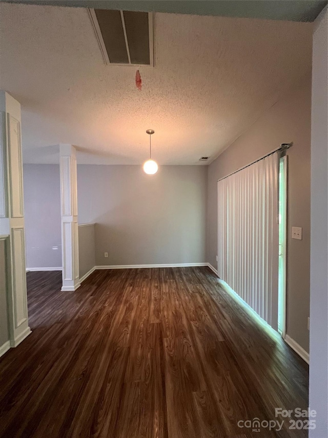 unfurnished dining area featuring dark wood finished floors, baseboards, and a textured ceiling