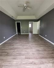 unfurnished living room featuring baseboards, wood finished floors, and ceiling fan