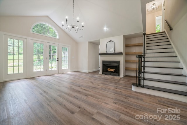 26056 Neptunes Lndg, Fort Mill, SC 29708 - unfurnished living room featuring a chandelier, a fireplace with flush hearth, high vaulted ceiling, wood finished floors, and stairway