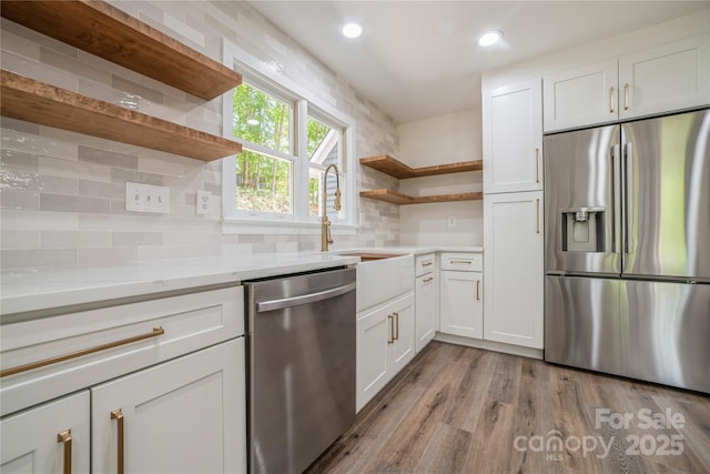 26056 Neptunes Lndg, Fort Mill, SC 29708 - kitchen with stainless steel appliances, open shelves, white cabinetry, light wood-type flooring, and decorative backsplash