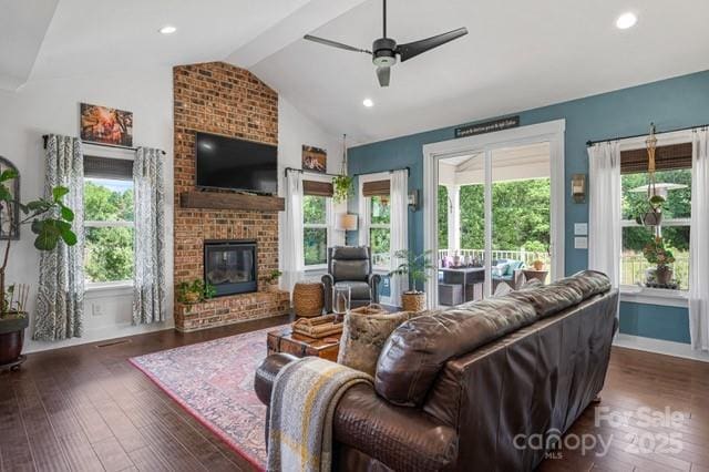 living area featuring lofted ceiling, baseboards, a fireplace, ceiling fan, and wood finished floors