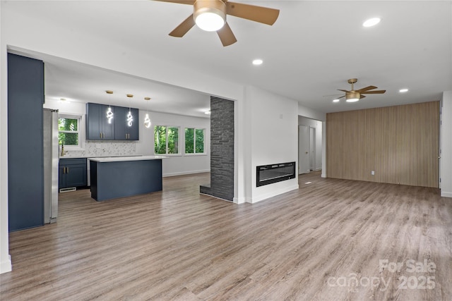 unfurnished living room with ceiling fan, plenty of natural light, light wood-style flooring, and recessed lighting