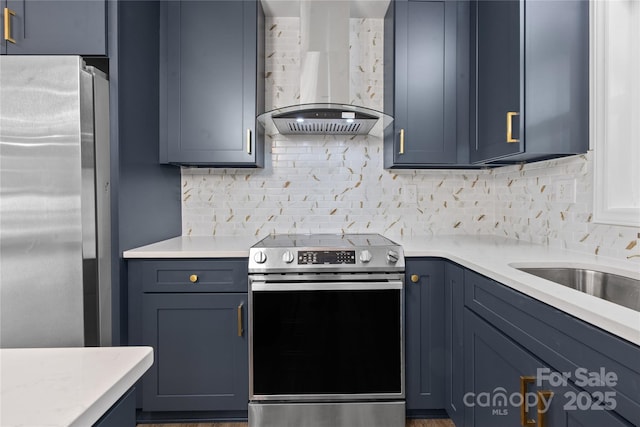 kitchen featuring appliances with stainless steel finishes, wall chimney exhaust hood, light countertops, decorative backsplash, and blue cabinetry