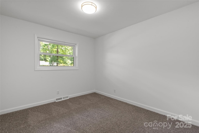spare room featuring carpet floors and baseboards
