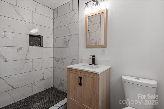 full bath featuring tiled shower, vanity, and toilet