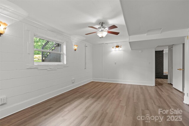 unfurnished room featuring wood finished floors, baseboards, ornamental molding, and a ceiling fan