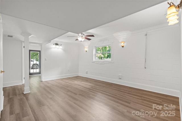 empty room with wood finished floors, crown molding, baseboards, ceiling fan, and plenty of natural light