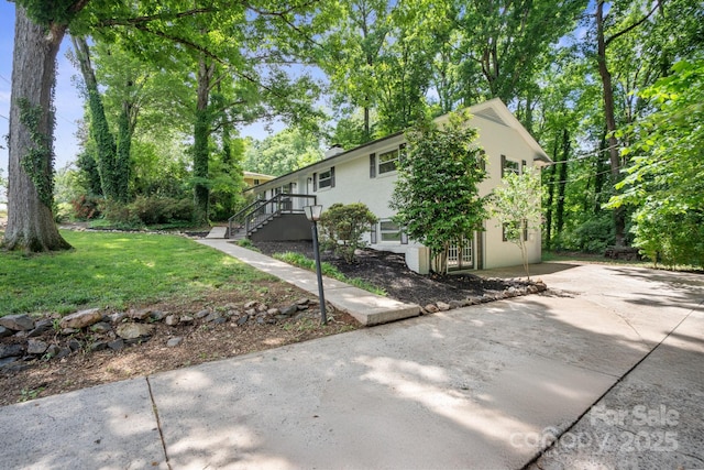 view of side of property with concrete driveway, stucco siding, and a yard