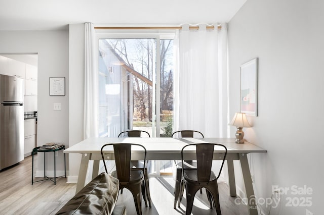 dining room featuring light wood finished floors and baseboards