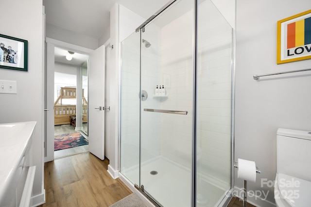full bathroom featuring wood finished floors, a stall shower, toilet, vanity, and ensuite bath