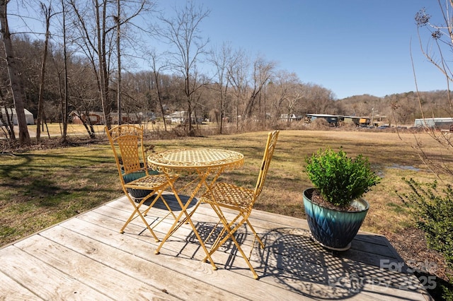 wooden terrace with a lawn and view of wooded area