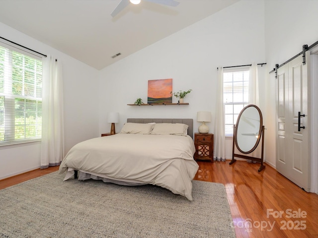 14336 Northridge Dr, Charlotte, NC 28269 - bedroom with a barn door, light wood-style flooring, multiple windows, and high vaulted ceiling