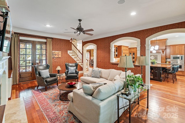 8534 Highgrove St, Charlotte, NC 28277 - living area with wallpapered walls, light wood-style flooring, arched walkways, a ceiling fan, and stairway