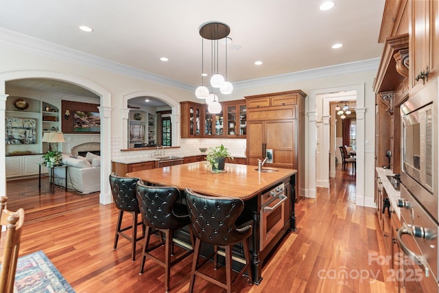 8534 Highgrove St, Charlotte, NC 28277 - kitchen featuring brown cabinetry, stainless steel appliances, a sink, a kitchen breakfast bar, and light wood-style floors