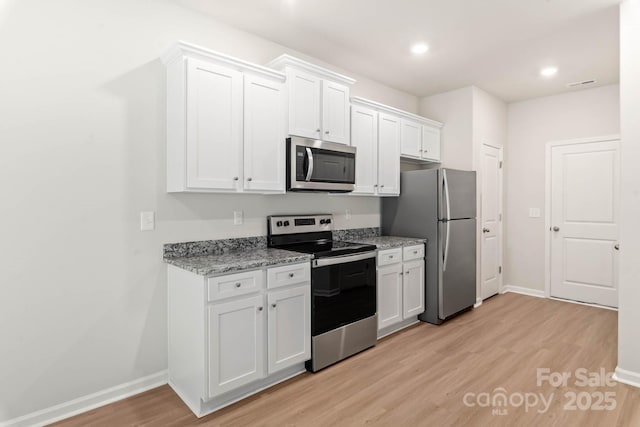 3334 Strong Box Ln, Gastonia, NC 28052 - kitchen with stainless steel appliances, baseboards, light wood finished floors, white cabinetry, and light stone countertops