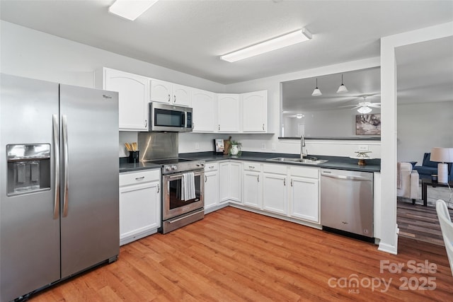 1961 Leesburg Dr, Clover, SC 29710 - kitchen featuring appliances with stainless steel finishes, a sink, dark countertops, light wood-style floors, and white cabinetry