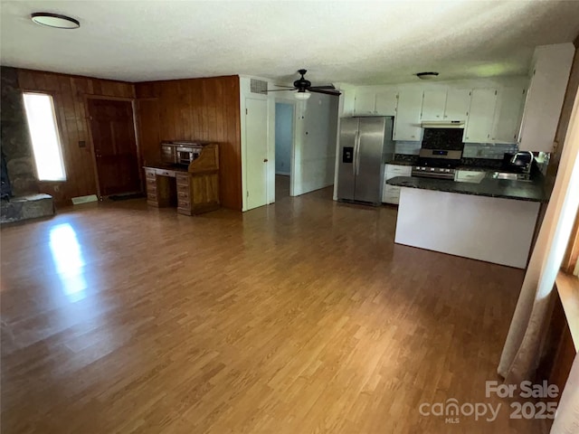 947 Ravendale Dr, Charlotte, NC 28216 - kitchen with appliances with stainless steel finishes, a sink, dark countertops, dark wood finished floors, and wood walls