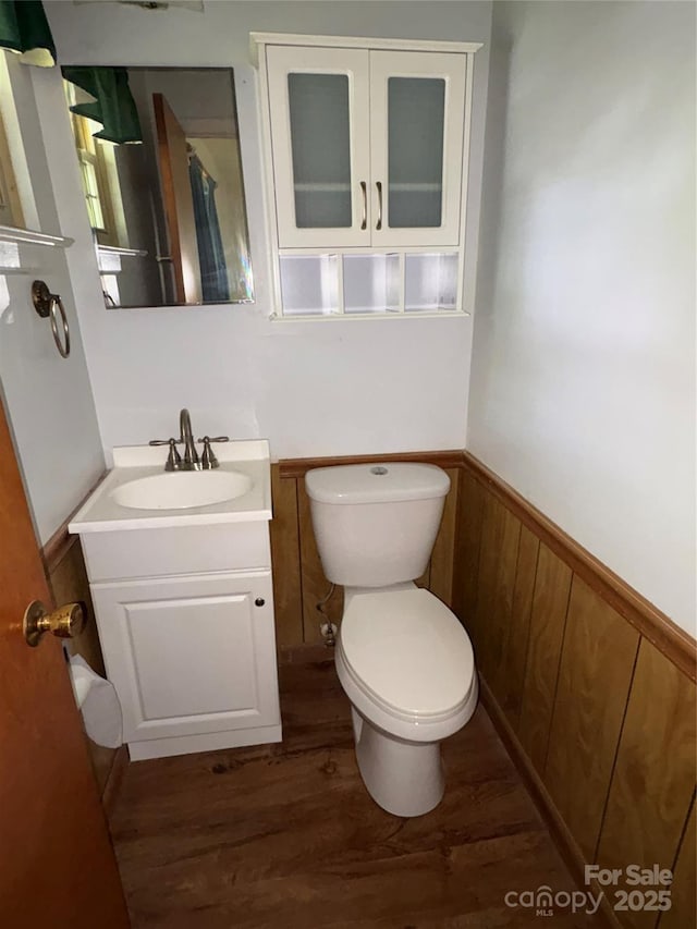947 Ravendale Dr, Charlotte, NC 28216 - half bath featuring wood finished floors, toilet, a wainscoted wall, and vanity
