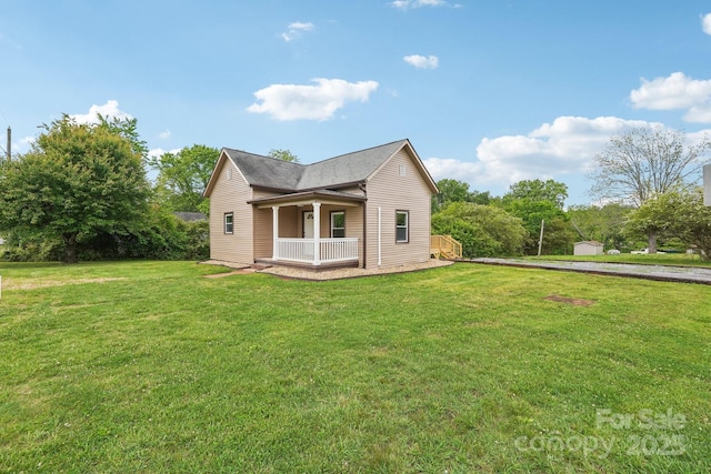view of side of property featuring covered porch and a lawn