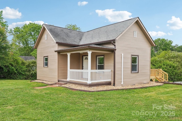 view of side of property featuring a porch, a lawn, and roof with shingles