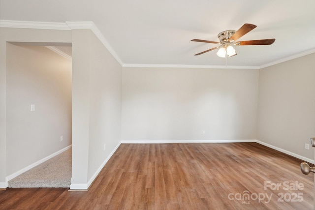 spare room featuring wood finished floors, a ceiling fan, baseboards, and crown molding