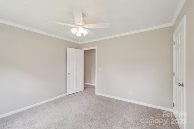 unfurnished bedroom featuring carpet flooring, ornamental molding, baseboards, and ceiling fan