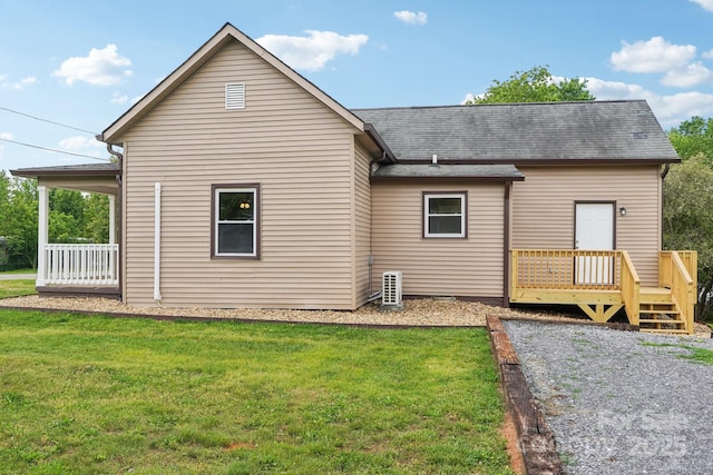 rear view of house with a yard, a wooden deck, and roof with shingles
