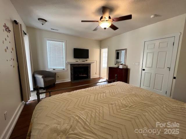 115 Breakaway Trl, Mars Hill, NC 28754 - bedroom featuring a fireplace with flush hearth, dark wood-type flooring, a ceiling fan, and baseboards